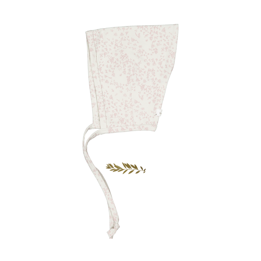 Side view of a pale pink baby pixie bonnet with a subtle scattered pattern and long ties.