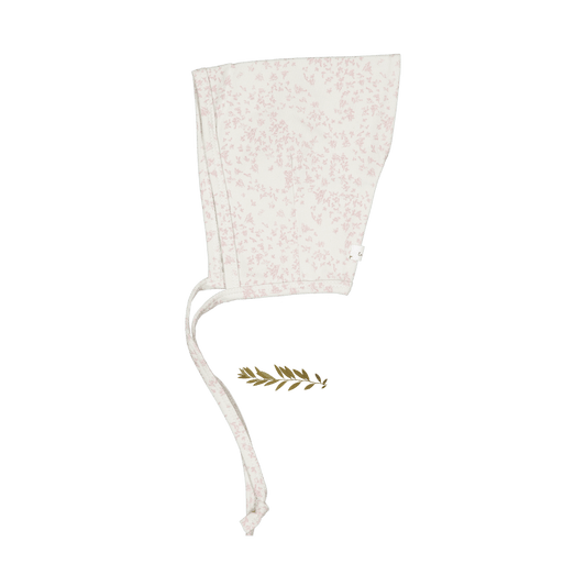 Side view of a pale pink baby pixie bonnet with a subtle scattered pattern and long ties.