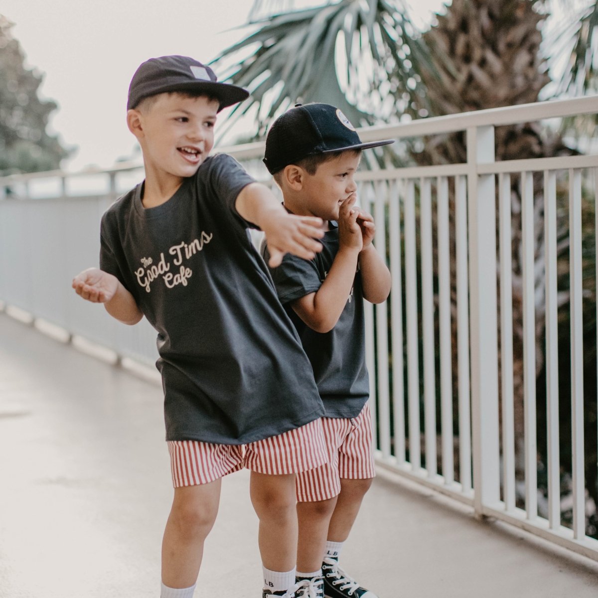 Two young boys wearing baseball hats having a good time wearing their matching vintage black shirts.